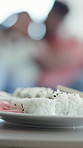 Closeup, food and sushi in home with chopsticks, culinary and couple with seafood cuisine. People, plate and rice at house with ginger, Japanese dish and raw fish nutrition for authentic delicacy 