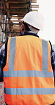 Engineer, man and walk at construction site with inspection, property development or renovation project. Back, person and PPE with civil engineering, quality assurance and outdoor for infrastructure.