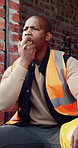 Builder, man and lunch break at construction site with building project, time management or helmet. Black person, eating apple or thinking outdoor with industrial job, PPE or check watch for schedule