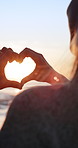 Sunset, couple and heart hands by beach with vacation, relationship commitment and bonding together. Married people, love sign and emoji by ocean with evening sunlight, holiday outdoor and flare.