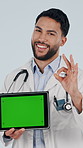 Face, tablet and happy doctor with green screen, ok sign and healthcare marketing in studio. Tech, man or medical worker with space, perfect emoji or point for telehealth ads on white background