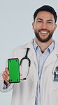 Face, phone and doctor with green screen in studio, healthcare and insurance marketing. Mobile display, happy man and medical worker with mockup space, laugh or telehealth ads on white background
