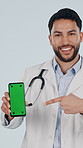 Face, phone and doctor point with green screen in studio, healthcare and insurance marketing. Mobile, happy man and medical worker with mockup space, thumbs up or telehealth ads on white background