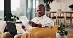 Laptop, remote work and document with black man on couch in living room for small business in home. Tech, paperwork and report with freelancer in apartment for startup research, proposal or review