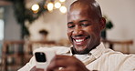 Happy, black man and relax in home with phone, social media and browsing website in living room. Smile, male person or reading at house with mobile, communication and download ebook for weekend break