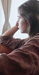 Sad, thinking and window with woman on sofa in home for regret, grief memory and reflection. Mental health, trauma and disappointment with person with depression in living room of apartment with fear