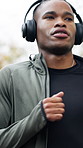 Cardio, man or running with headphones at park for exercise routine, fitness challenge or playlist. Athlete, black person or workout in nature with music streaming, physical activity and morning jog