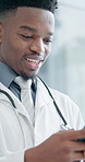 Doctor, typing and black man with phone in hospital for communication or network connection. Male person, healthcare worker or smile with mobile smartphone for online texting or chatting in office