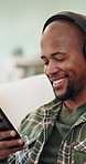 Happy, music or black man listening with headphones in home for audio streaming or playlist. Male person, user or smile with mobile app or phone on sofa for sound quality, network or podcast in house