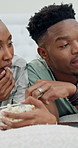 Talking, bedroom and black couple with popcorn for streaming, watching movie and video together. Laptop, relax and man with woman with snack, conversation and bonding with series on weekend in home