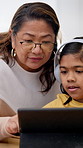 Grandmother, child and tablet with headphones for elearning, homework assistance or study support. Asian family, senior woman and kid with tech in home for online lesson, assignment help or education