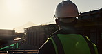 Architect, helmet and thinking with building on construction site for safety or security. Back view, male person or contractor with hard hat for architecture, infrastructure or civil engineering
