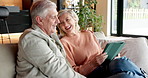 Tablet, home and senior couple relax together on lounge sofa to scroll online, social media or connection. Laugh, funny post and people on couch for technology app, communication or retirement