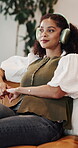 Woman, thinking and smile with headphones in lounge, relax and listening to music with subscription. Streaming, audio and happy person with nostalgia, laughing or reflection with radio sound in house
