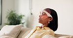 Red light, skincare and woman on sofa with mask for beauty, relax or wellness with collagen production. Health, calm and person in living room with LED phototherapy for dermatology treatment in home.