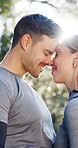 Fitness, love and happy couple with forehead kiss in nature for affection, romance or intimacy. Active, man or woman with smile, hug or lens flare for outdoor bonding, commitment or embrace in forest