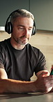 Music, kitchen and man with phone, dance and listening to radio playlist on streaming service app. Mobile, headphones and mature person in home with audio subscription, smile and sound on internet