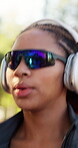 Headphones, running and sunglasses with woman outdoor in nature for exercise routine. Cardio, music and shades with runner person in forest for commitment or dedication to physical health activity