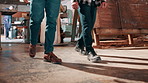 Carpentry, walking and legs of men in workshop for manufacturing, timber business and woodwork. Team, contractor and people in warehouse for wood production, furniture restoration and collaboration