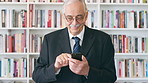 Professor, typing and happy man with phone in library for academic study, knowledge or information. Male person, mature teacher or scrolling with smile on smartphone for online curriculum or syllabus