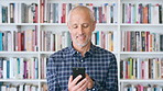 Teacher, mature and happy man with phone in library for academic study, knowledge or information. Male person, user or professor scrolling with smile on smartphone for online curriculum or syllabus