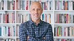 Publisher, office and face of man with crossed arms for career, opportunity and job at agency. Creative, happy and portrait of person by bookshelf for publicist, managing editor and publication house
