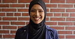 Education, face and funny with Muslim woman on brick wall background at college campus. Belief, laughing and learning with student at university for Arabic, Islamic or religious studies as scholar