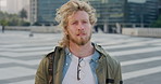 Commute, face and windy with student man in city for education, learning or study opportunity. Backpack, campus and hair with person outdoor in urban town for morning travel to college or university