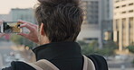Travel, photo or man in city with phone screen, online memories or post update on weekend break. Digital, back or person in town with tech, social media picture or memory capture on tourist trip.