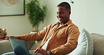 Laugh, laptop and man on sofa for internet, online streaming and connection on weekend. Home, happy and African person on computer for website, communication and funny videos to relax in living room