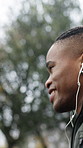Exercise, man or running with earphones in rain for fitness dedication, pace training or playlist. Active, black person or winter workout at park with music, endurance challenge or health discipline