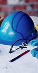 Helmet, construction and blueprint on table with safety documents, architecture or building design. Floor plan, paperwork and hard hat for ppe, equipment and tools for infrastructure development