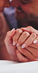 Love, couple and holding hands in bedroom for trust together, commitment and care in morning. Man, woman and connection with partner on bed to relax, romantic relationship and support at home