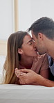 Couple, kiss and holding hands on bed, home and bonding with partner on break or laughing in bedroom. Love, connection and affection for spouse, support and happy people on weekend and relax in house