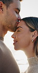 Smile, travel and couple with kiss on beach for romance, date and anniversary vacation or bonding together. Sunset, love and happy people with affection for weekend holiday, loyalty and support