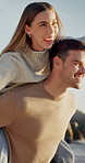 Happy, couple and playful by ocean with piggyback, bonding together and energy for freedom on vacation. People, date and outdoor on beach with fun relationship, holiday and wellness on weekend trip.