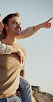 Happy, couple and point by ocean with piggyback, bonding together and love for connection on vacation. Low angle, people date and outdoor on beach with relationship, holiday and wellness on weekend.