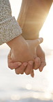Sunset, travel and couple holding hands on beach for romance, date and vacation or bonding together. Sunshine, love and people with affection for weekend holiday, loyalty and anniversary support