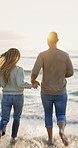 Couple, running and holding hands in ocean with sunset, bonding together or wellness on holiday trip. Flare, people dating and playful outdoor by beach with fun relationship, connection and vacation.