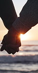 Sunset, love and couple holding hands on beach for romance, date and vacation or bonding together. Sunshine, travel and people with affection for weekend holiday, loyalty and anniversary support