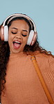 Woman, dancing and excited with headphones in studio for music, streaming and smile on blue background. Girl, happy person and listening to song, sound and audio subscription for moving body
