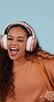 Woman, dancing and audio with headphones in studio for music, streaming and excited on blue background. Girl, person and listening to song, sound and subscription for moving body with smile or energy