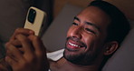 Night, relax or happy man with phone in bedroom for online browsing, network or adult website. Male person, smile and biting lip with mobile smartphone in bed for social media, internet or connection
