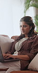 Earphones, laptop and woman on sofa for remote work, research and planning with podcast in home. Typing, music and person on computer for copywriting, website content and online project with audio