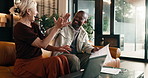 Finance, documents and couple with high five in home for winning, good news or profit together. Interracial relationship, man and woman with laptop or smile for financial success or bonus in house