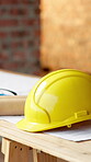 Helmet, blueprint and table at construction site for planning, renovation or property development. Hard hat, floorplan and safety equipment at worksite for compliance, remodeling or civil engineering