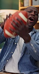 American football, watching tv and man with ball celebration in home for goal, team win or excited. Sport fan, happy black person or suspense with friends for live streaming, game scoring or support