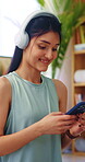 Fitness, music and phone with happy woman in home to download or search for yoga tutorial. App, headphones and typing with person in apartment for health activity, online subscription or wellness