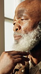 Window, thinking and senior man in home, contemplating and remember past memory on break and lonely. Sad, reflection and elderly black person with thoughts, regret and pondering decision in house