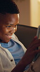 Night, tablet and smile with black child on sofa in home for esports app, online gaming and relax. Gamer subscription, virtual competition and late with kid in living room of house for streaming